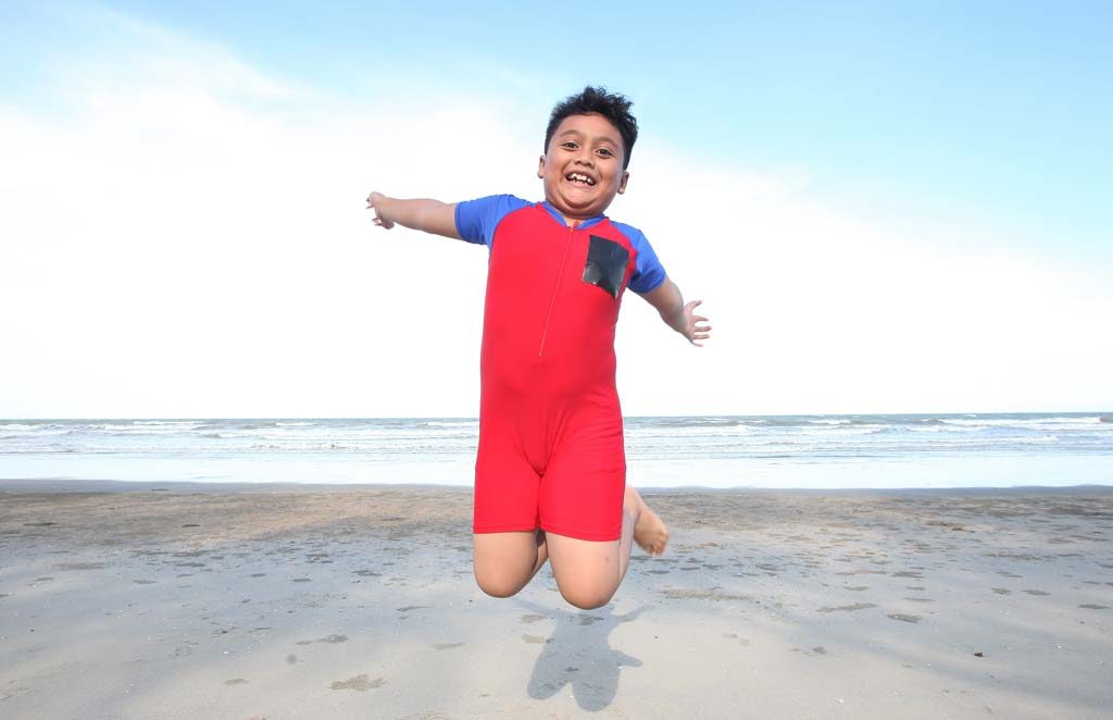 Happy kid excercising jumping on beach