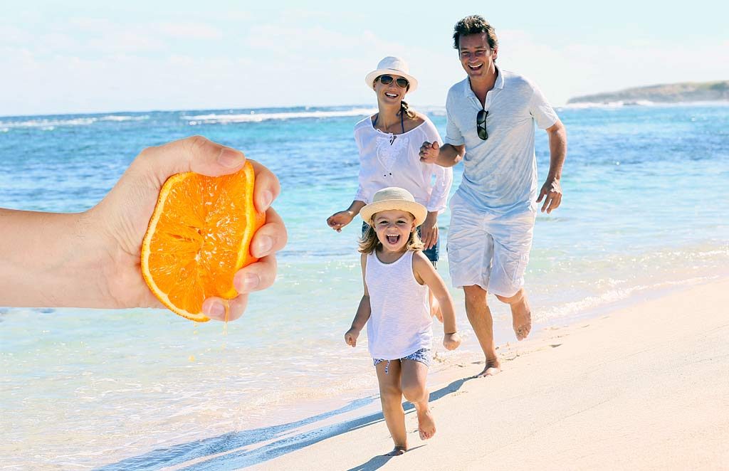 Orange being squeezed on the beech with happy family running